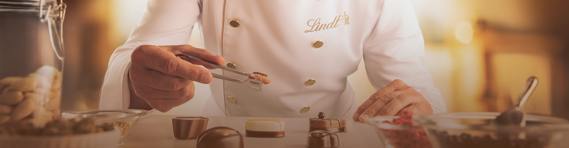 Maître chocolatier Urs Liechti decorating truffles holding an almond in pincers (Photo)